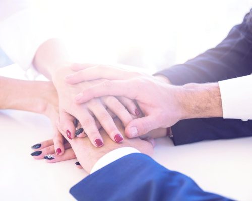 businesspeople-stacking-each-other-s-hand-white-desk-scaled-freshblue